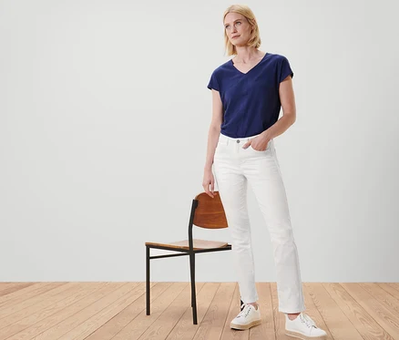 Eine Frau posiert neben einem Stuhl und trägt Jeans – Fit »Kira« und eine Webhose.