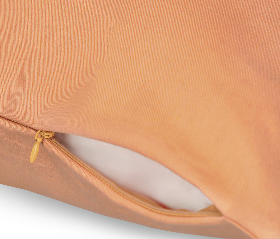Detailaufnahme eines lachsfarbenen Kissenbezugs mit Reißverschluss. Sichtbarer Bezug der Marke SCHÖNER WOHNEN.