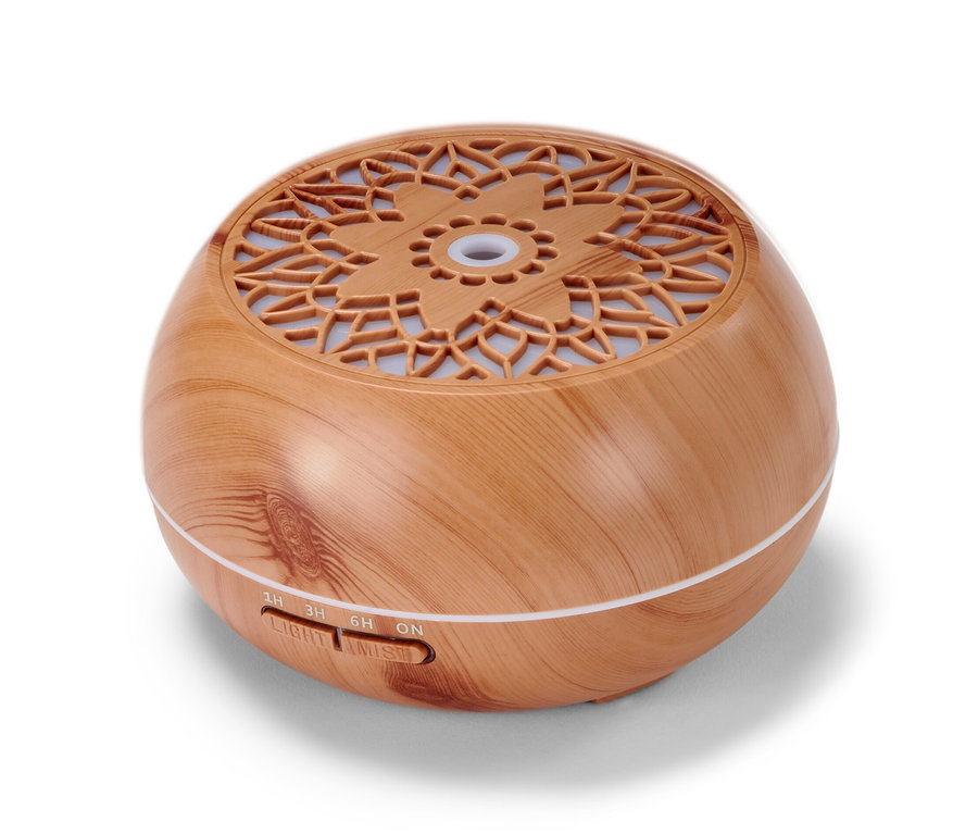 Ein Aroma-Diffusor mit Bluetooth®-Lautsprecher in Holzoptik und kreisförmigem Muster auf der Oberseite.