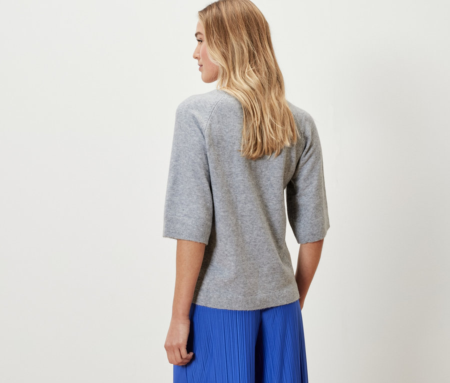 Frau trägt einen grauen Strickpullover.