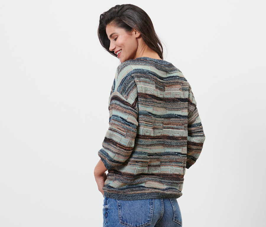 Frau schaut nach unten und posiert in einem Strickpullover.