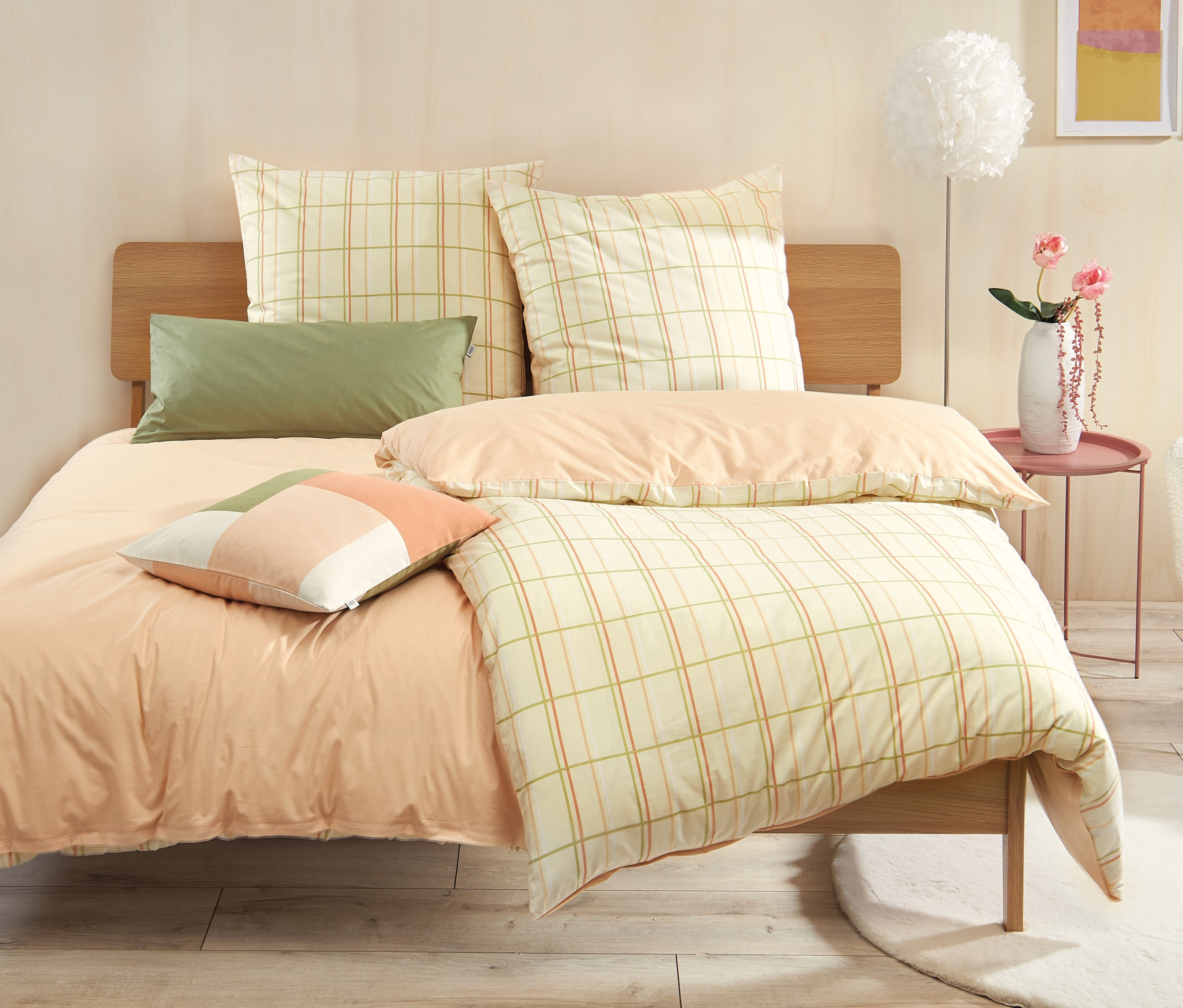 Bett mit SCHÖNER WOHNEN Renforcé-Bettwäsche in Übergröße und Normalgröße, kariert, mit grünen Kissen.