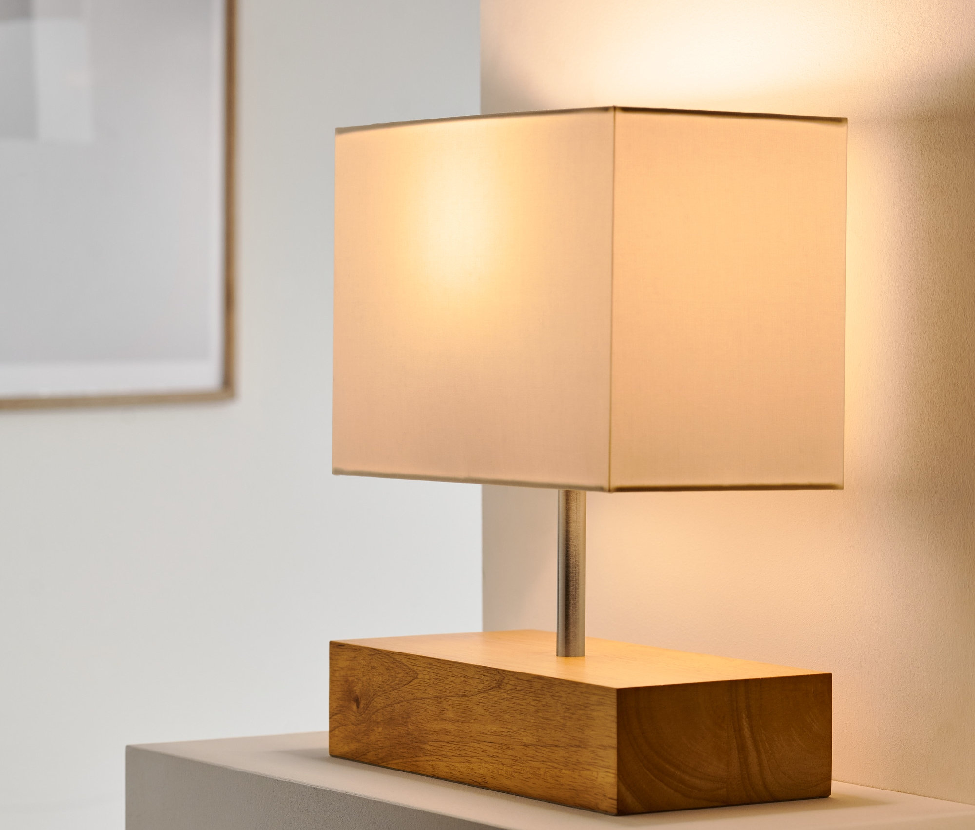 Tischleuchte mit Holzfuß steht auf einer weißen Oberfläche.