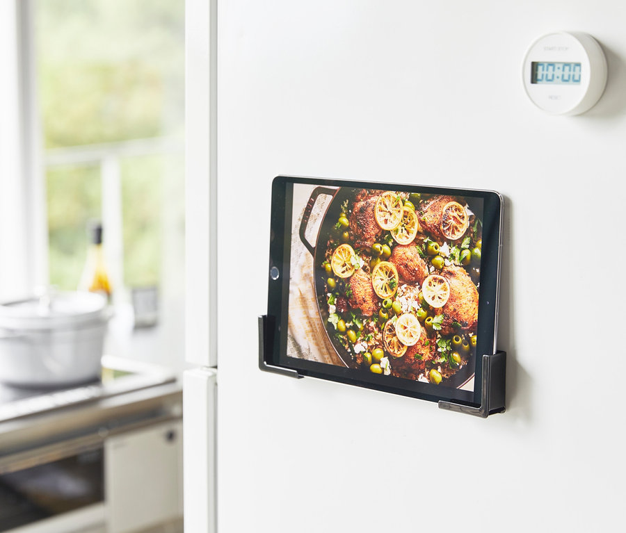 Tablet mit Essensrezept im schwarzen YAMAZAKI Tablethalter »TOWER« am weißen Kühlschrank.