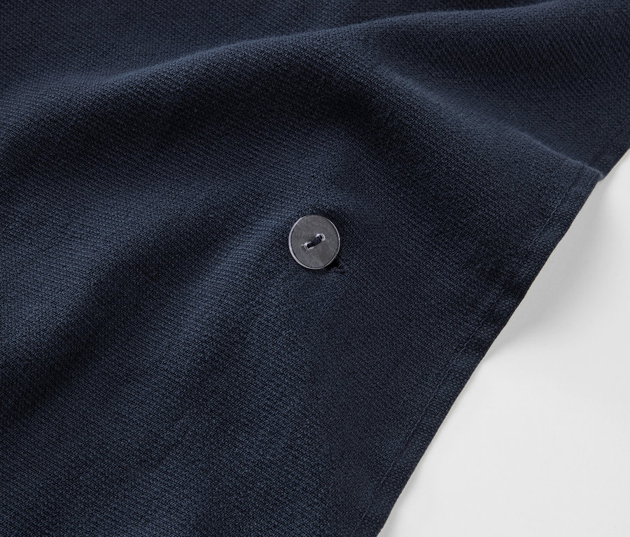 Detailaufnahme eines marineblauen 2-in-1-Badetuch-und-Ponchos mit Knopf.