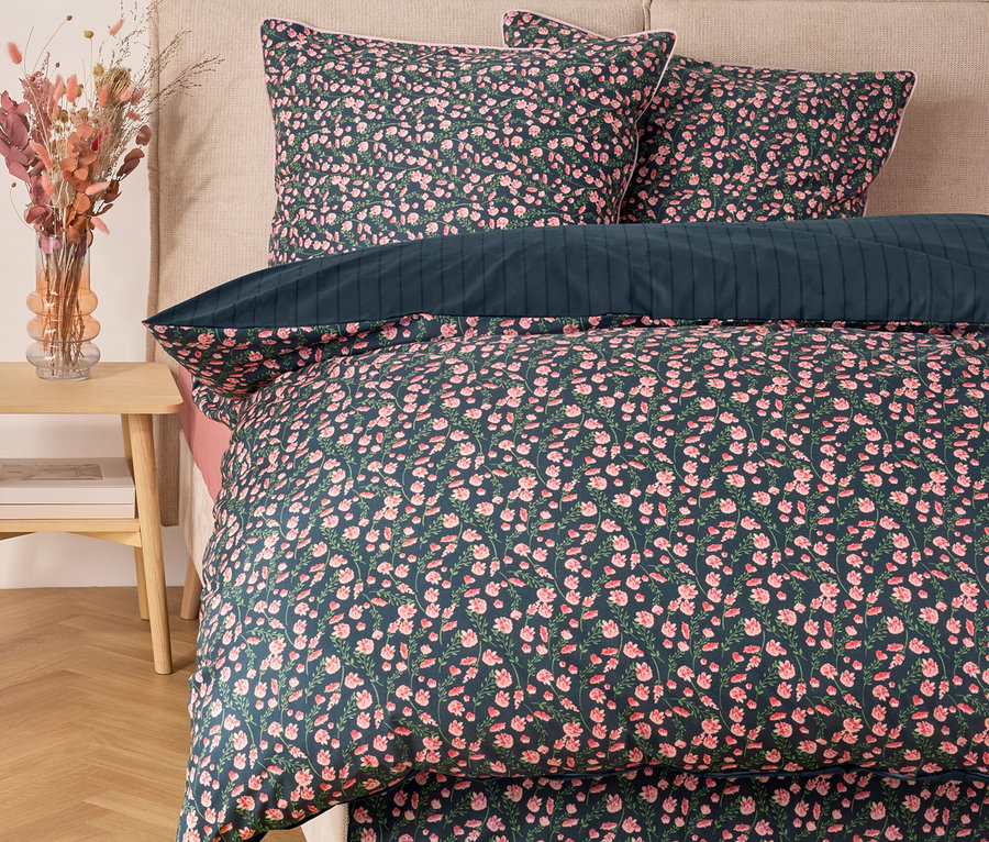 Blumige Bettwäsche mit Kissen auf einem Bett.