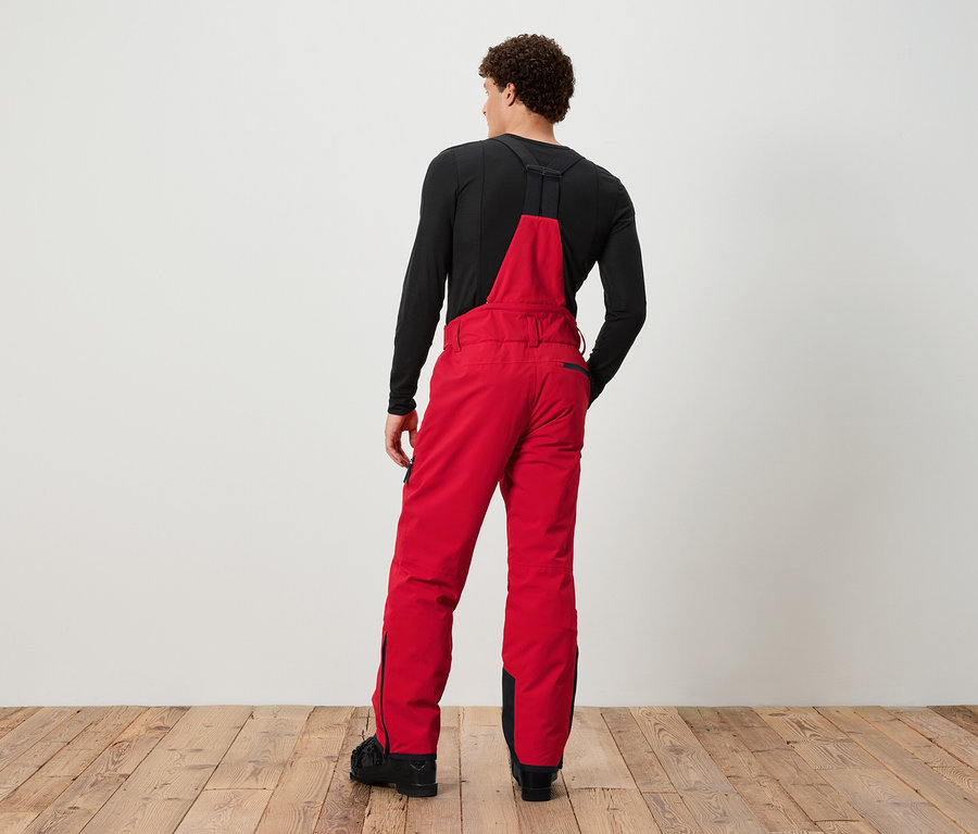 Mann von hinten mit roter Skihose mit Latz und schwarzem T-Shirt.