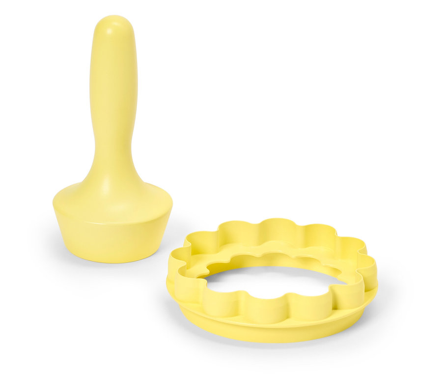 Gelber Teigausstecher mit Griff und runder Ausstecher mit gewelltem Rand auf weißem Hintergrund.