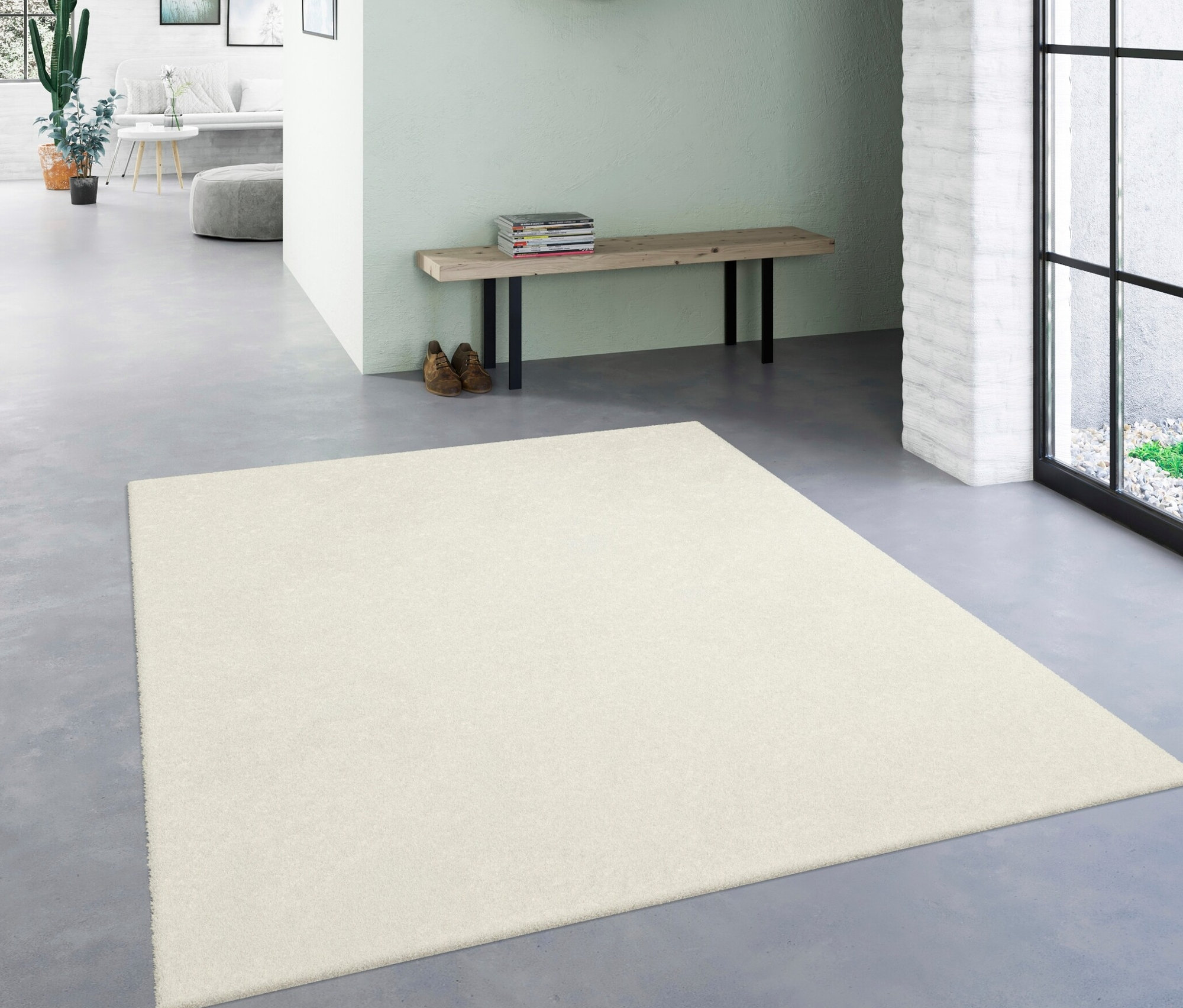Ein wollweißer Teppich »Mellow« liegt in einem Flur. Im Hintergrund eine Bank mit Schuhen und Spiegel.