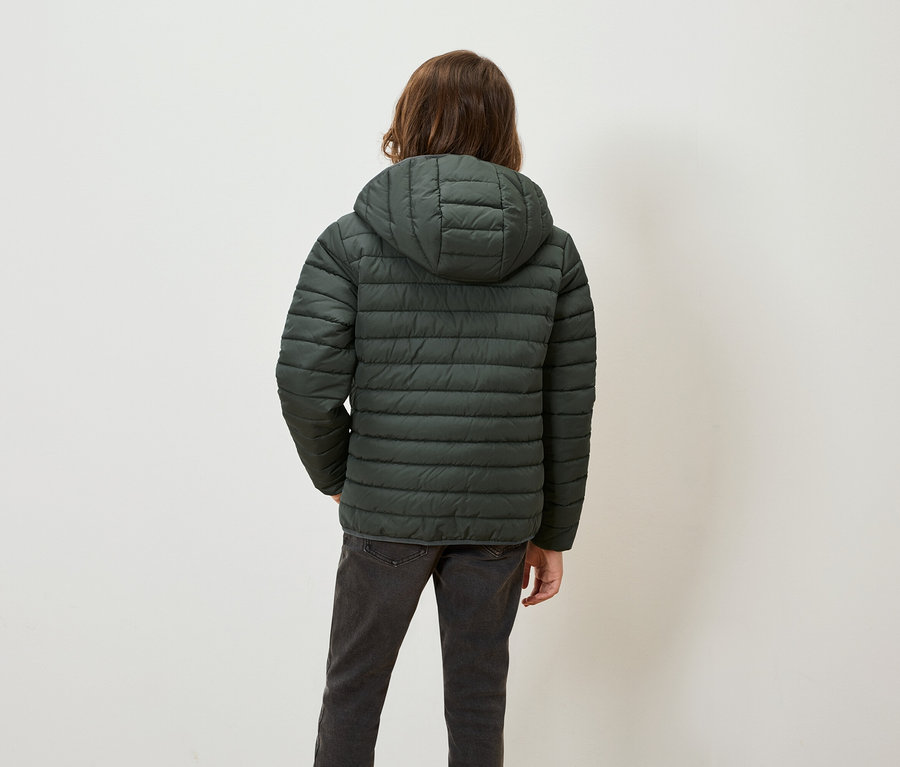 Von hinten ist eine Person mit braunen Haaren in einer grünen Daunenjacke mit Kapuze und grauen Jeans zu sehen.