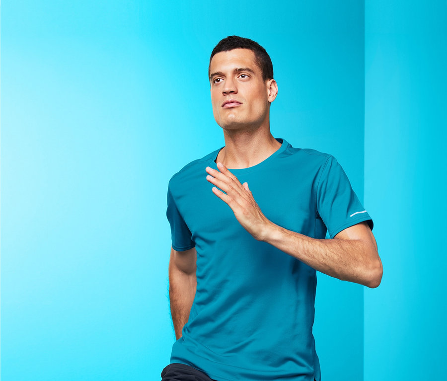 Mann in blauem Funktionsshirt und schwarzen Shorts läuft vor blauem Hintergrund.