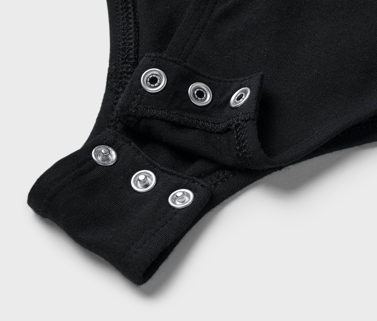 Detailaufnahme eines schwarzen Bodys mit Druckknöpfen im Schritt.