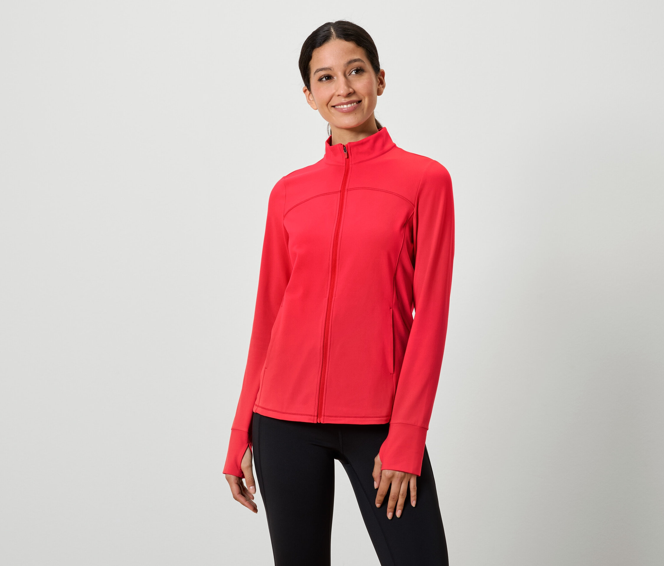 Frau trägt eine rote Reißverschlussjacke und schwarze Leggings.