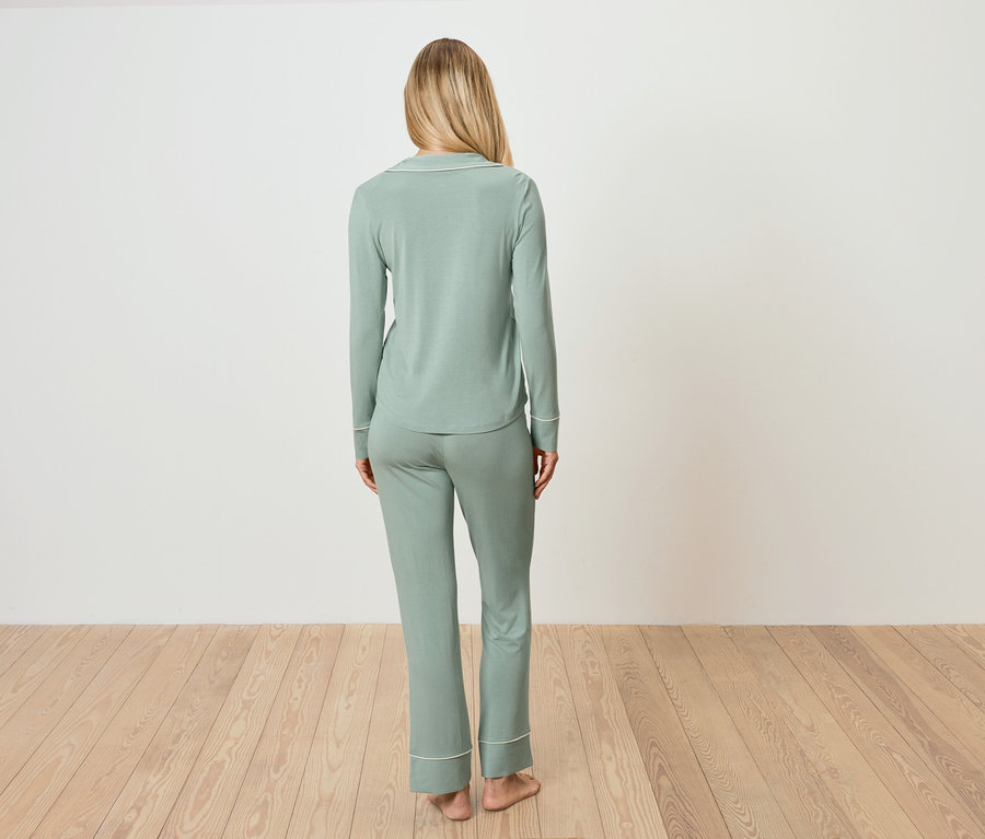 Frau steht mit dem Rücken zur Kamera und trägt einen hellgrünen Pyjama.