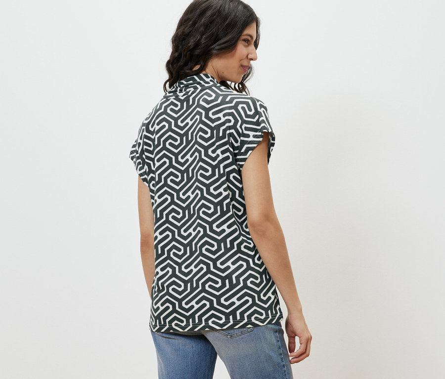 Profilansicht einer Frau, die ein grünes Blusenshirt mit V-Ausschnitt und Jeans trägt.