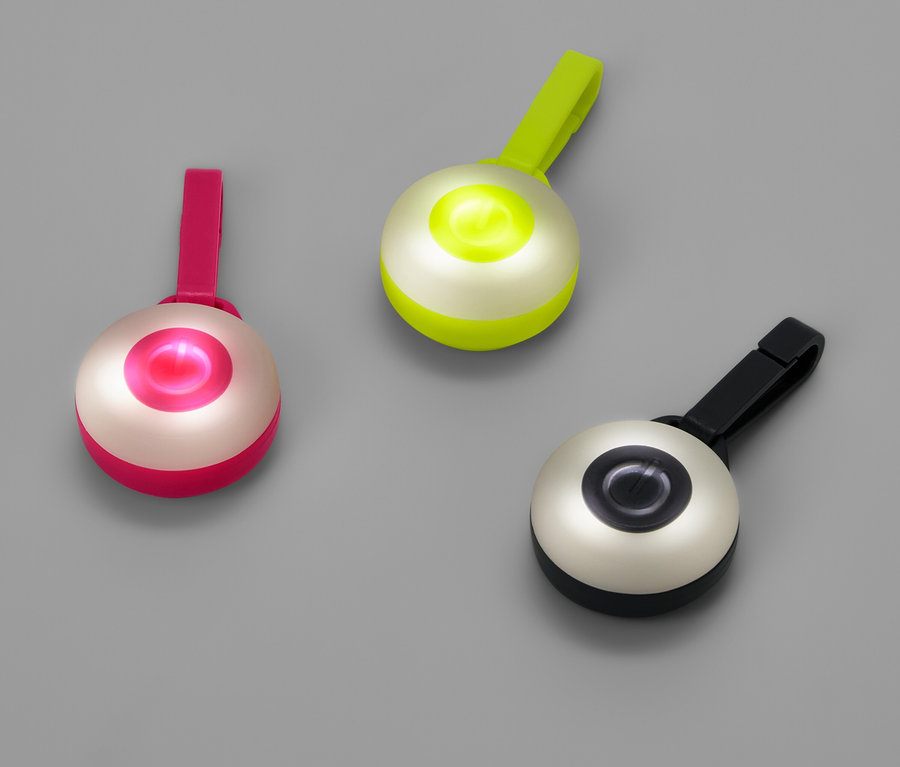 Drei runde Lichter mit Clips in Pink, Grün und Schwarz auf grauem Hintergrund.