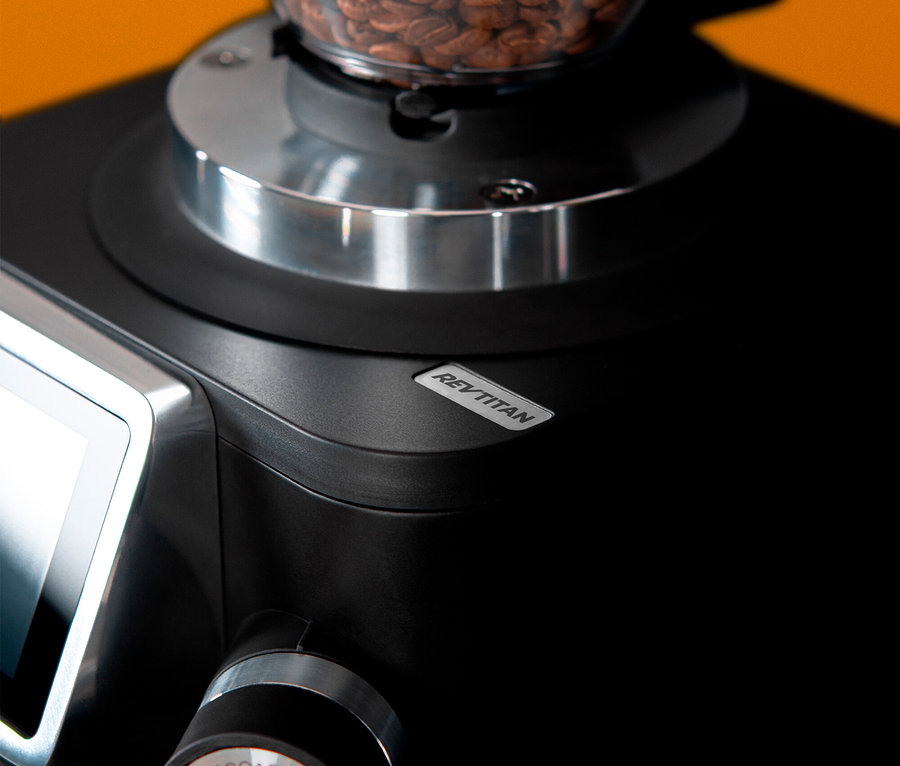 Nahaufnahme einer schwarzen Rev Titan Kaffeemühle mit Kaffeebohnen im Behälter.