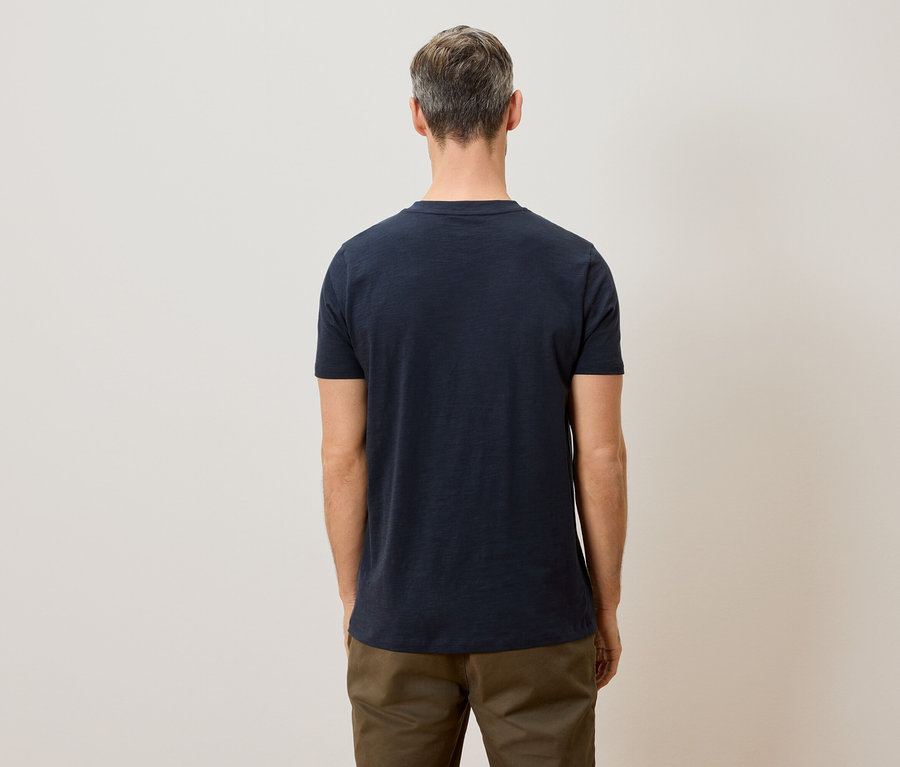 Mann von hinten mit einem dunkelblauen T-Shirt und einer khakifarbenen Hose.