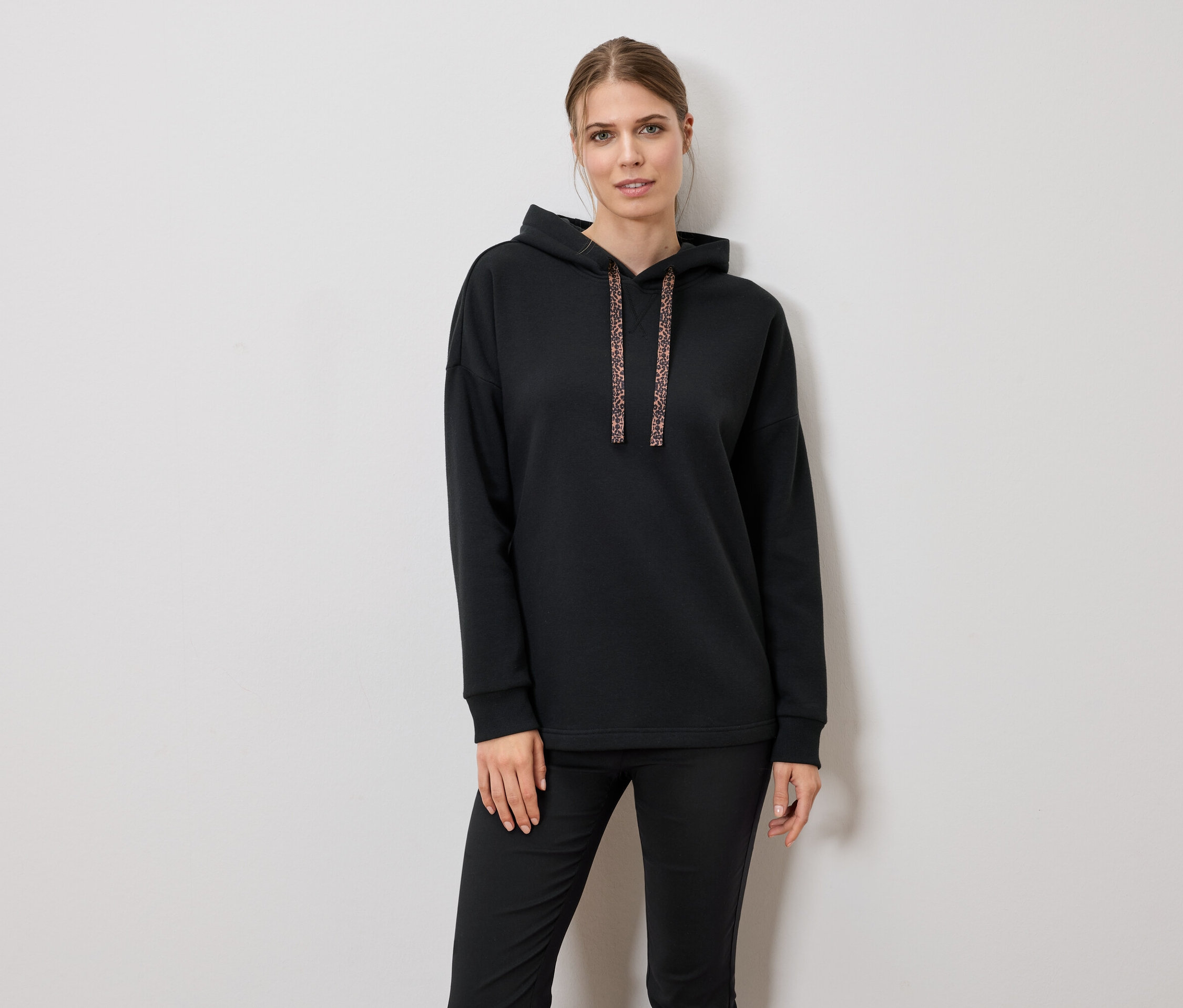 Frau trägt schwarzen Hoodie und Hose.