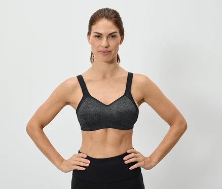 Frau mit den Händen auf den Hüften, die einen grauen Sport-BH trägt.