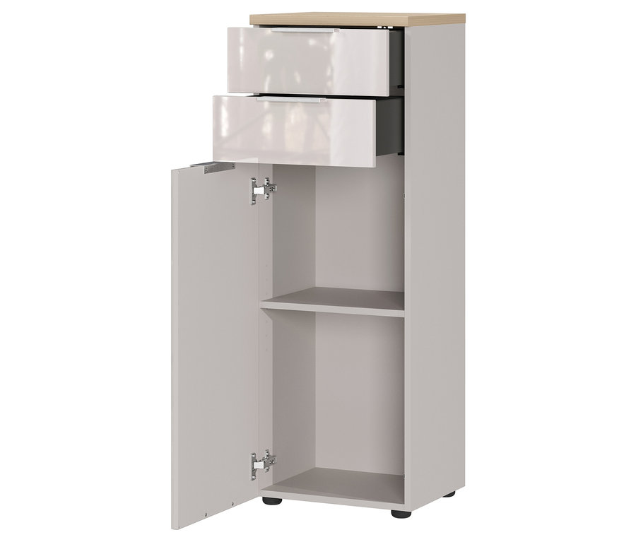 Ein schmaler grauer Schrank mit zwei Schubladen und einer offenen Tür, die zwei Regale zeigt.
