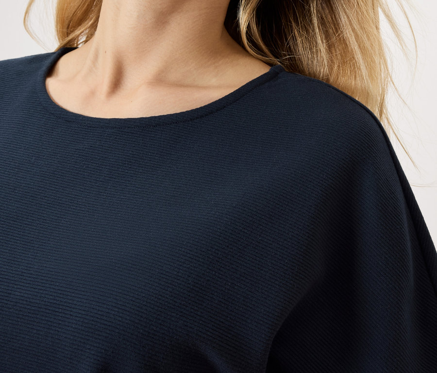 Nahaufnahme einer Frau, die ein marineblaues Oberteil trägt.