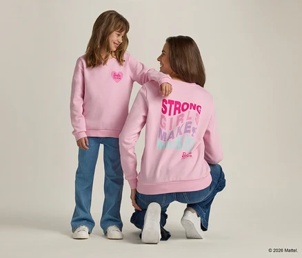 Mädchen mit Arm auf Schulter einer hockenden Frau, beide tragen rosa Sweatshirts und Jeans.