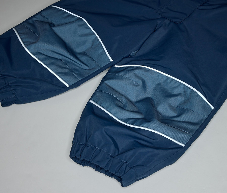 Nahaufnahme einer dunkelblauen Hose mit hellblauen Kniepatches und weißen Streifen auf grauem Hintergrund.