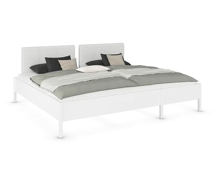 Weißes Doppelbett mit zwei Kopfstützen, grauen Decken und Kissen.