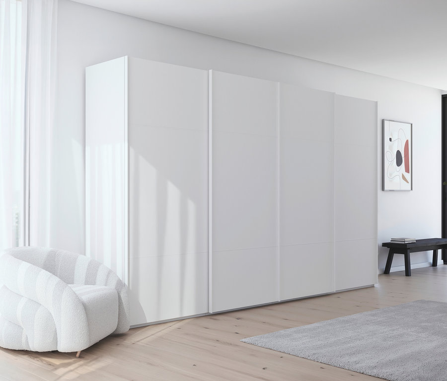 Ein weißer Sessel steht vor einem großen, weißen Schrank mit Schiebetüren in einem hellen Raum.