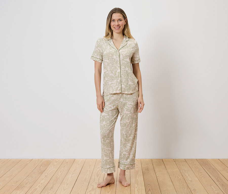 Frau in hell gemustertem Pyjama-Set aus Oberteil mit Knopfleiste und Hose.
