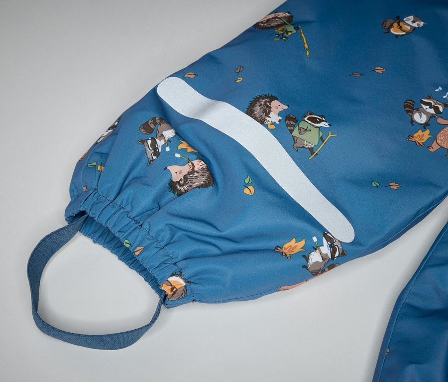 Nahaufnahme eines blauen Overalls mit Bären-, Waschbär- und Igelmuster, einem weißen Streifen und einem elastischen Knöchelriemen.