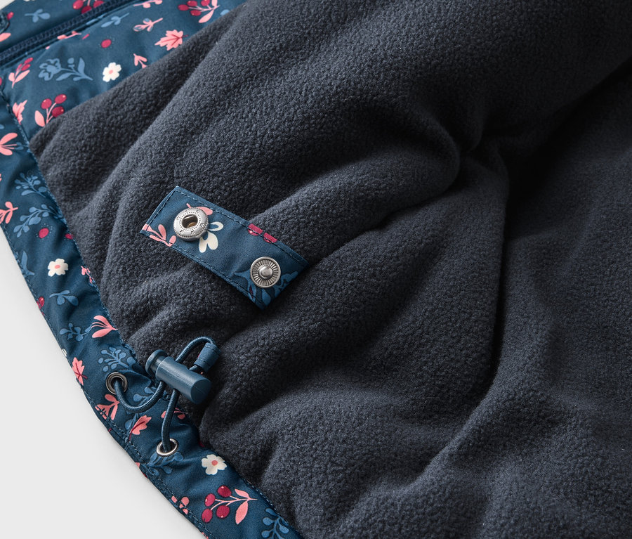 Detailansicht einer marineblauen Jacke mit Blumenmuster und Fleece-Futter, mit Kordelzug und Druckknopf.