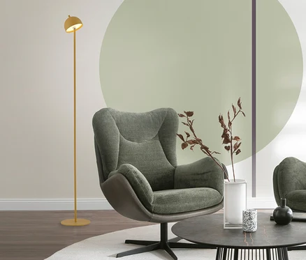 Ein Wohnzimmer mit einem grünen Sessel, einem runden Couchtisch mit Deko und einer gelben SCHÖNER WOHNEN-Kollektion Akku-Stehleuchte »Bellis«. Die Leuchte steht links neben dem Sessel.