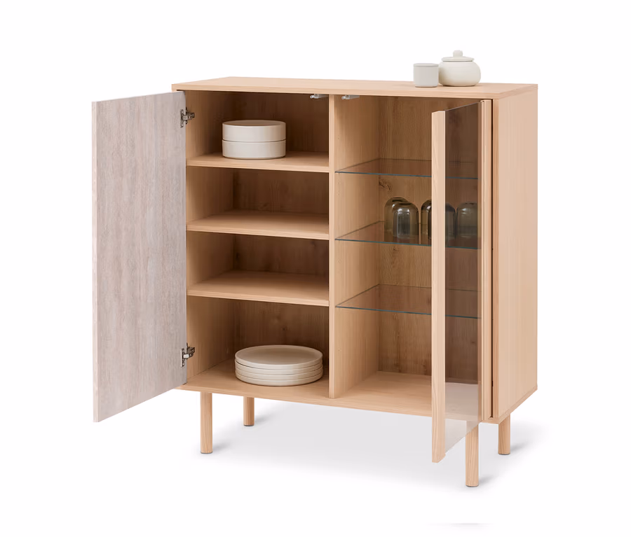 Heller Holzschrank mit zwei offenen Türen, einer Holztür und einer Glastür. Innen sind Teller und Gläser, oben stehen eine Tasse und ein Topf.