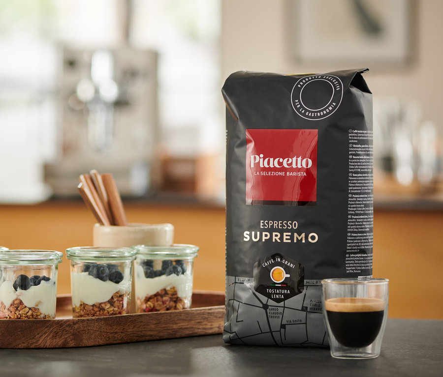 Auf einem Tisch stehen vier Gläser mit Joghurt und Blaubeeren, eine Packung Piacetto Espresso Supremo und eine Tasse Espresso.