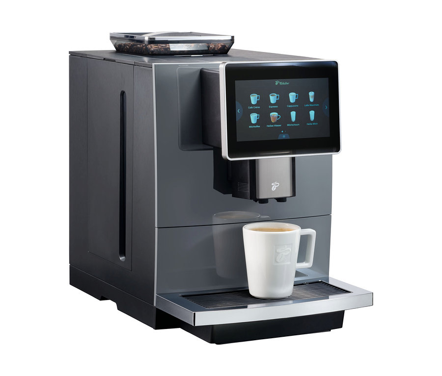 Grauer Profi-Kaffeevollautomat »Tchibo Office« inkl. Wasserfilter mit Tasse Kaffee.