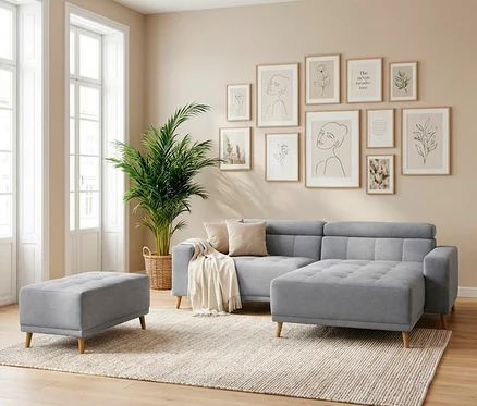 Modernes Wohnzimmer mit einer grauen Eckcouch und einem passenden Hocker auf einem hellen Teppich. An der Wand hängen elf gerahmte Bilder mit minimalistischen Illustrationen, daneben steht eine große Palme.
