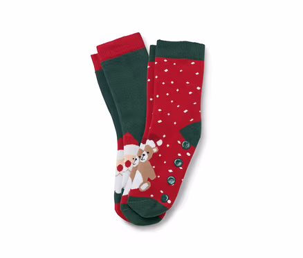 Zwei Paar Weihnachtssocken. Ein Paar ist grün mit rotem Rand und einem Bild von Santa Claus und einem Teddybär. Das andere Paar ist rot mit weißen Punkten und grünem Rand und Knöpfen.
