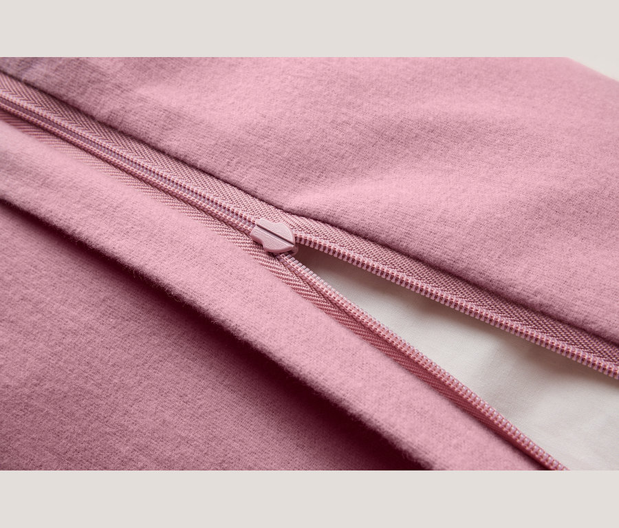 Nahaufnahme eines rosa Stoffes mit einem teilweise geöffneten rosa Reißverschluss, der ein weißes Futter darunter zeigt.