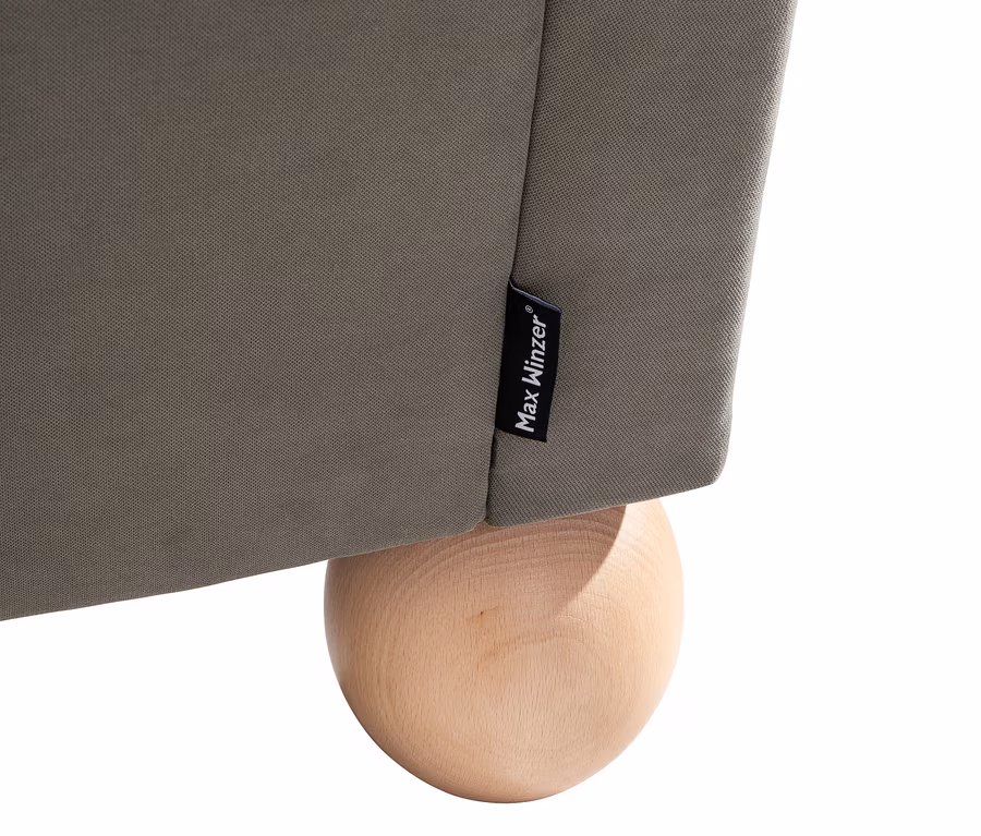 Detailansicht eines grauen XXL-Ohrensessels "Harvard" von Max Winzer® mit einem Holzbein.