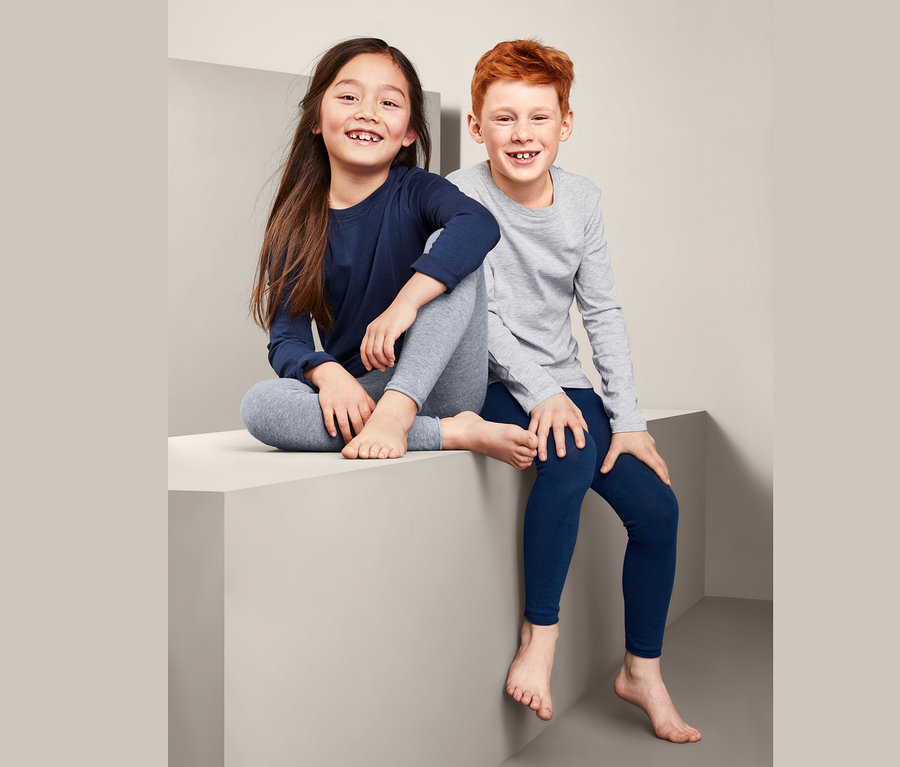 Zwei Kinder sitzen auf einem Quader und tragen 2 Strickleggings.