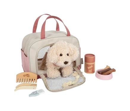 small foot Plüschhund mit Tasche und Pflege-Set: Ein cremefarbener Plüschhund sitzt in einer beigefarbenen und rosa Tragetasche, umgeben von Holzkamm, Nagelschere, Thermometer, Futterbehälter, rosa Napf mit Knochenleckerlis und Seilspielzeug.