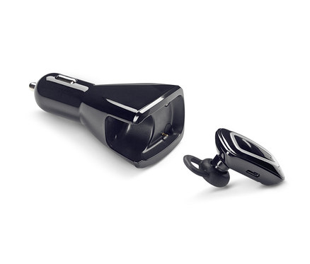 Ein schwarzes In-Ear-Freisprechanlagen-Set mit Kfz-Ladestation liegt auf einem weißen Hintergrund.