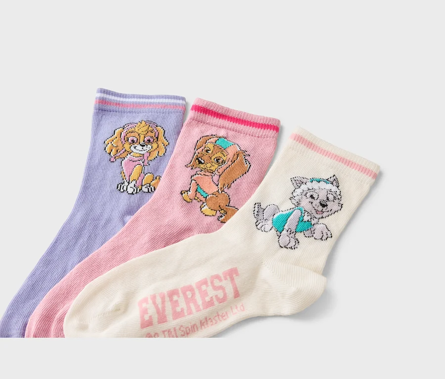 Drei Socken liegen nebeneinander: eine lavendelfarbene Socke mit einem Skye-Motiv, eine rosa Socke mit einem Motiv von Everest und eine cremefarbene Socke mit einem Everest-Motiv.