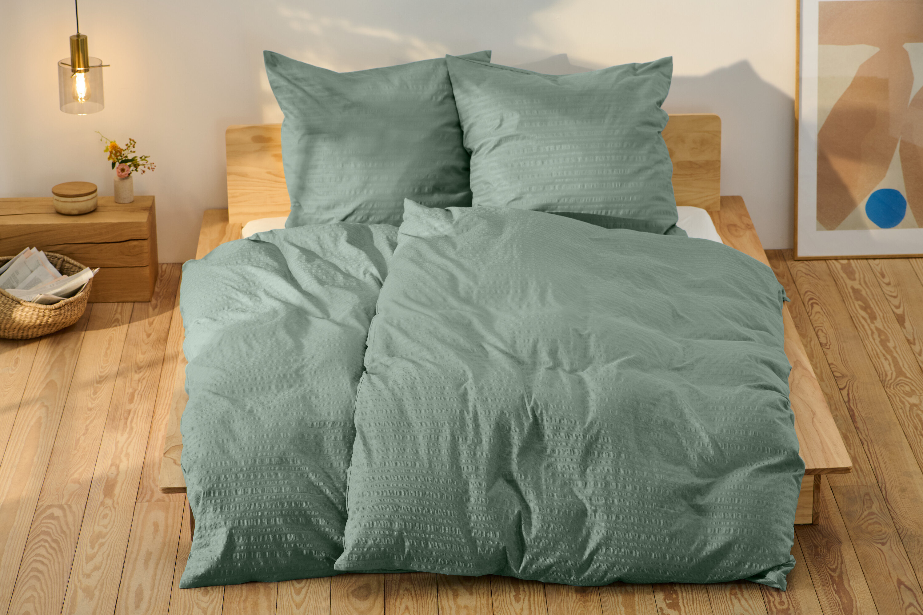 Grüne Seersucker-Bettwäsche in Normalgröße und eine in Übergröße auf einem Bett.