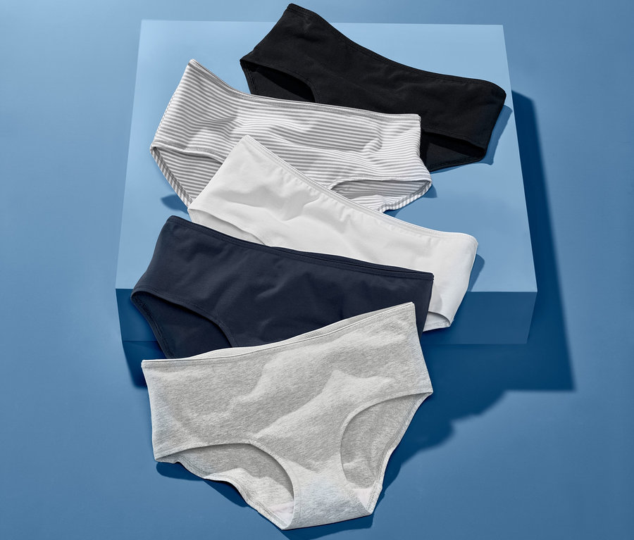 Fünf verschiedenfarbige Pantys liegen auf blauem Hintergrund. Das Set beinhaltet schwarze, gestreifte, weiße, dunkelblaue und graue Pantys.