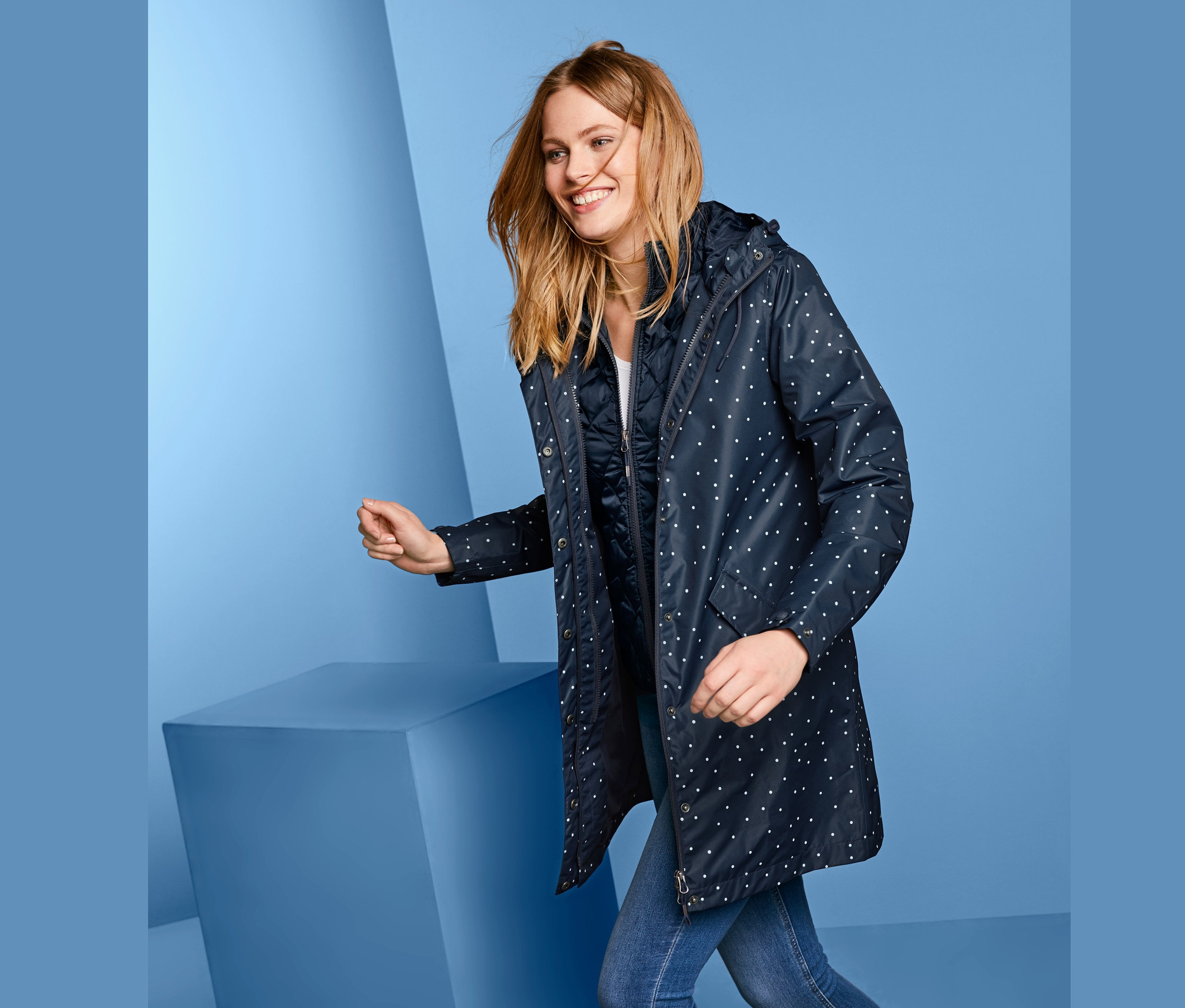 Frau trägt einen 3-in-1-Regenmantel mit weißen Punkten.