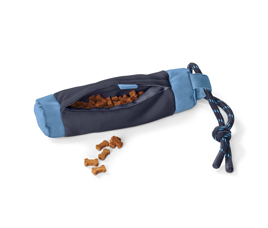 Ein Hundespielzeug-Futterdummy liegt auf der Seite, knochenförmige Leckerlis fallen aus der Öffnung.