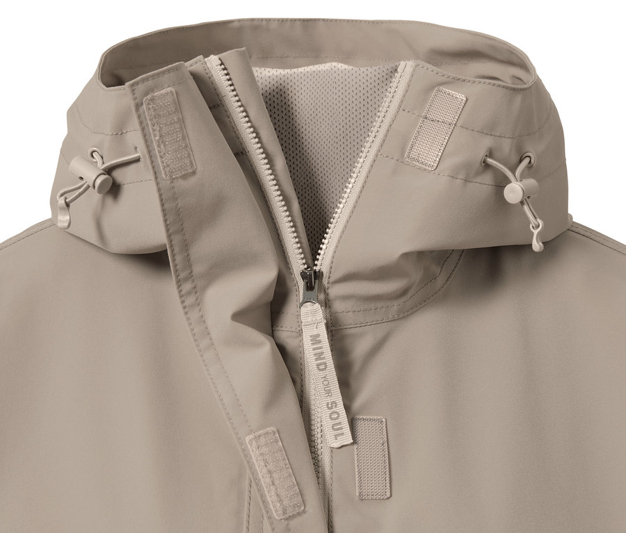 Detailaufnahme einer beigen Oversized-Funktionsregenjacke mit Reißverschluss.